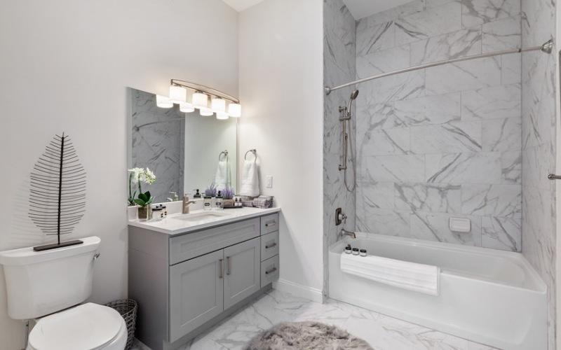 bathroom with marble tiling and bathtub