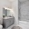 bathroom with vanity, marble shower tiling and bathtub